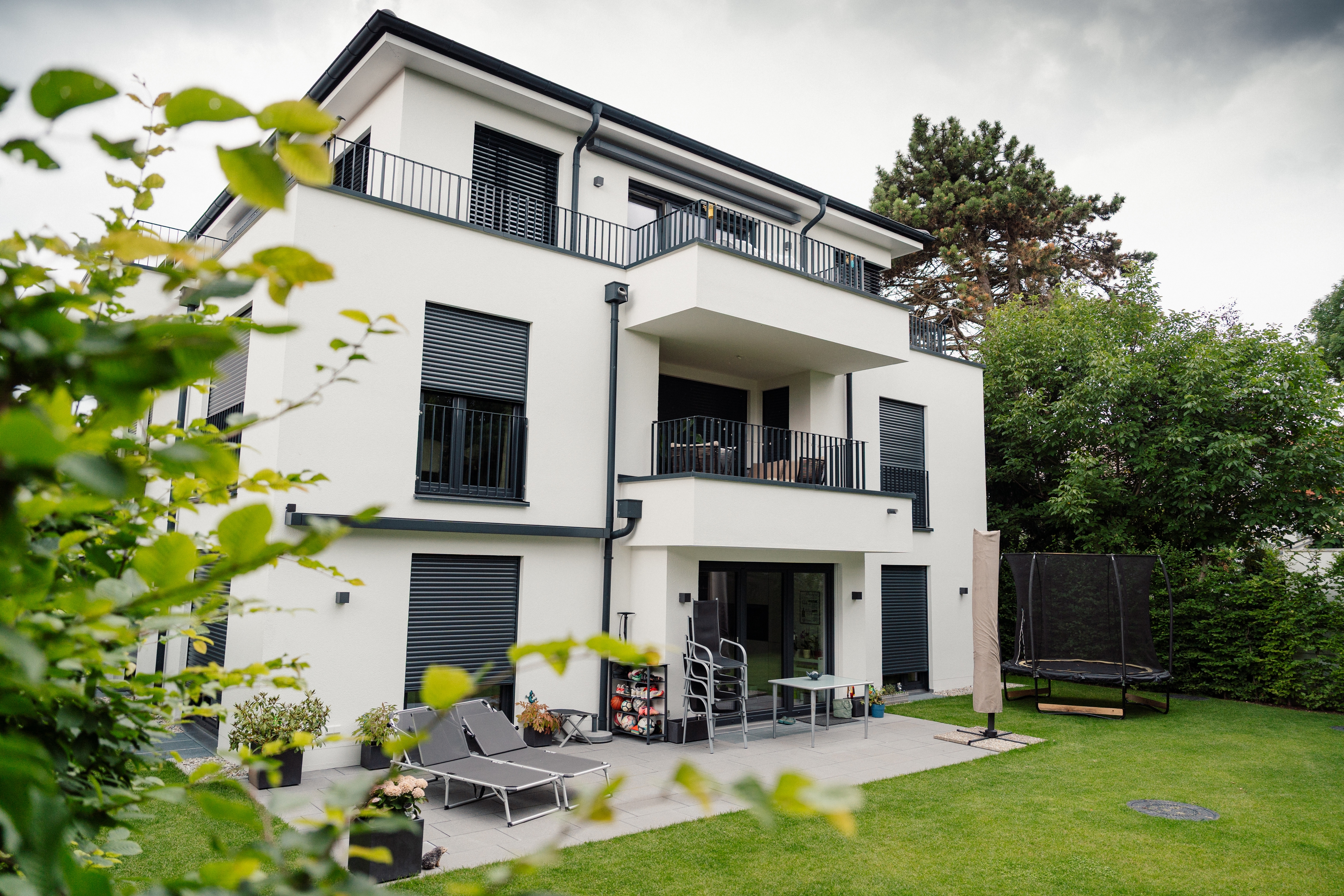 Mehrfamilienhaus mit Balkonen und Terrasse – Gartenansicht