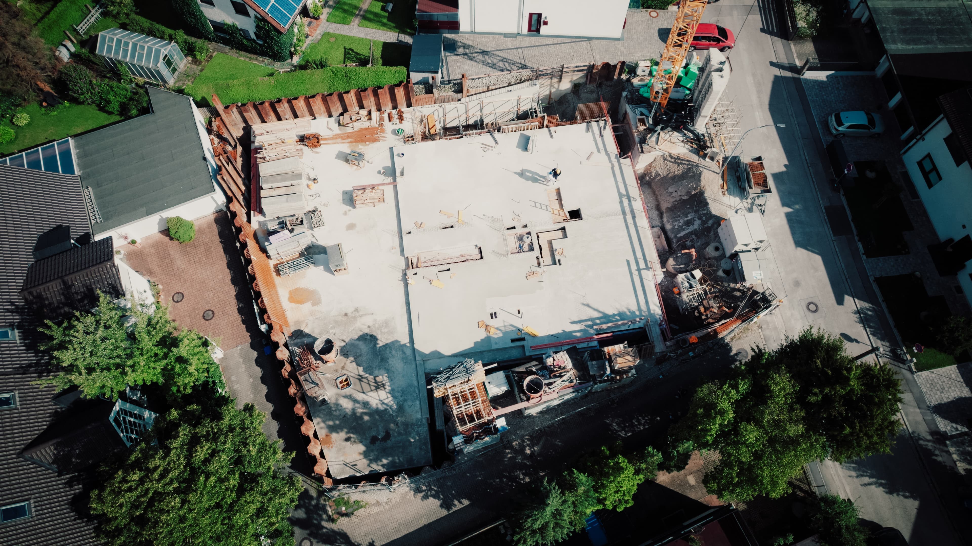 Luftaufnahme einer Baustelle: Rohbau-Decke mit Bewehrungsstahl; zwei Personen mit Bauhelmen besprechen die Arbeiten