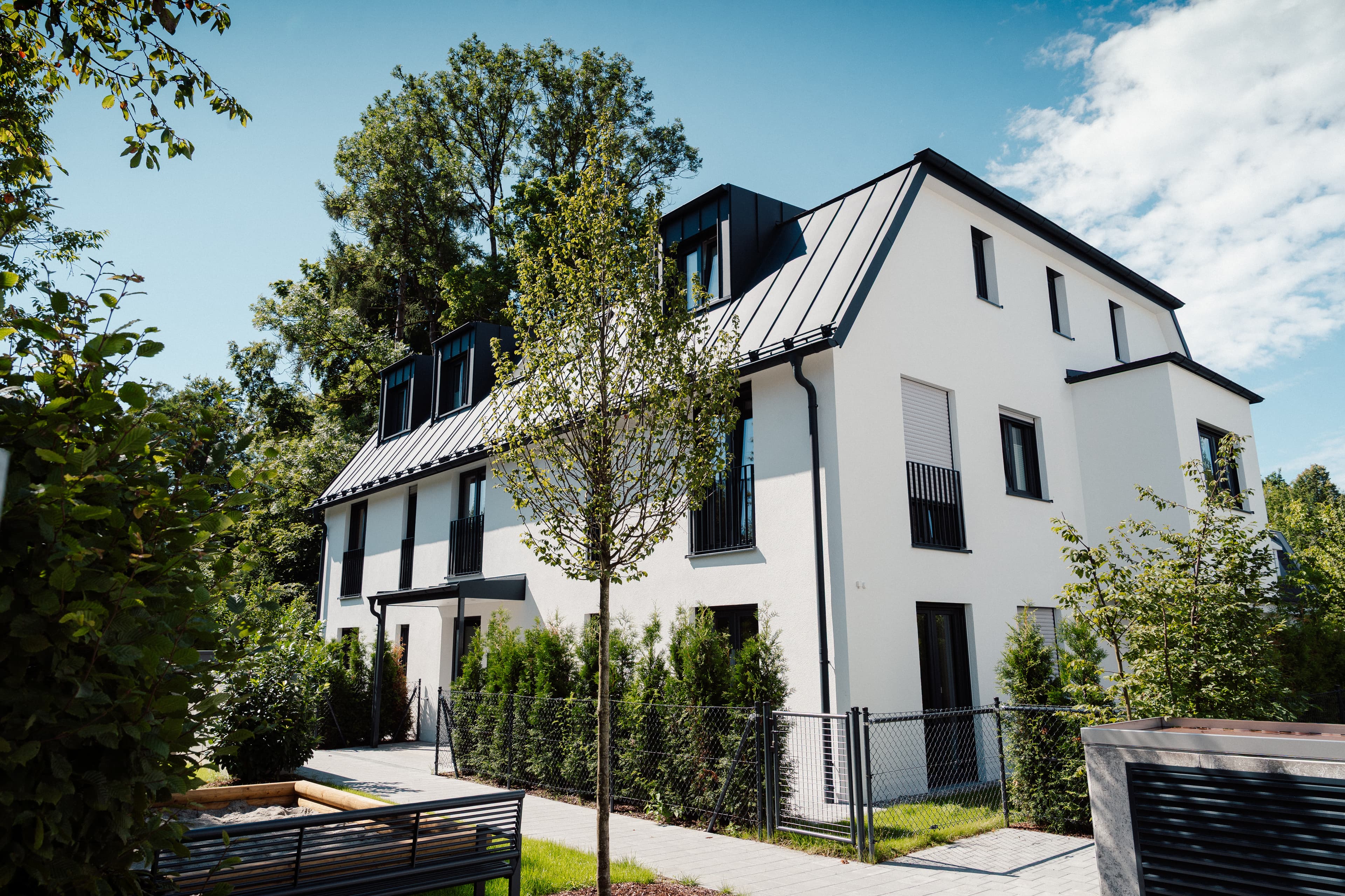 Sperberstraße 42 – Gartenansicht des Mehrfamilienhauses mit Weg und Hecken